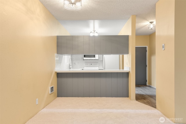 kitchen with a textured ceiling, white appliances, visible vents, and a sink