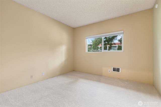 carpeted empty room featuring visible vents and a textured ceiling