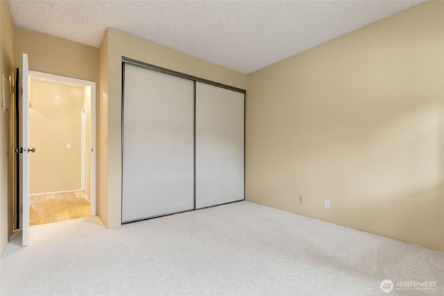 unfurnished bedroom featuring carpet, a closet, and a textured ceiling