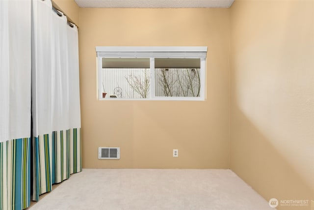 unfurnished room featuring visible vents, a textured ceiling, and carpet flooring