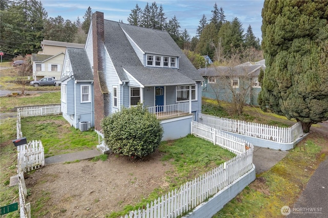 bungalow-style house featuring cooling unit, covered porch, a shingled roof, fence private yard, and a chimney