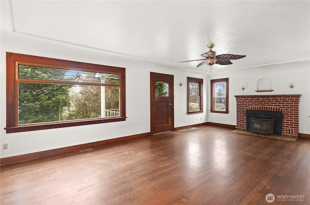 unfurnished living room with ceiling fan, visible vents, plenty of natural light, and wood finished floors