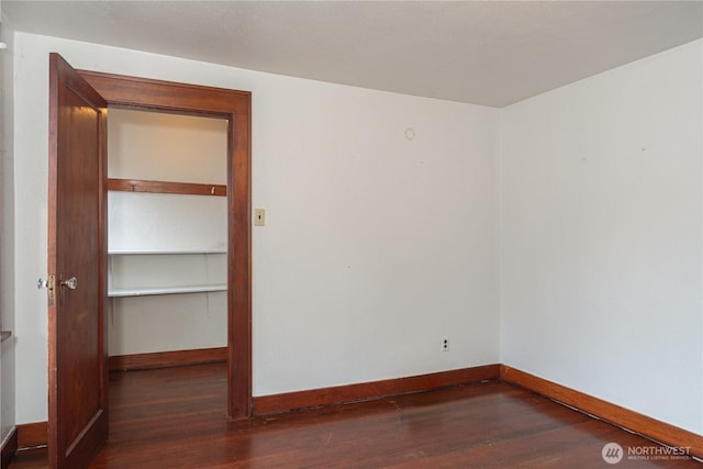 spare room featuring baseboards and wood finished floors