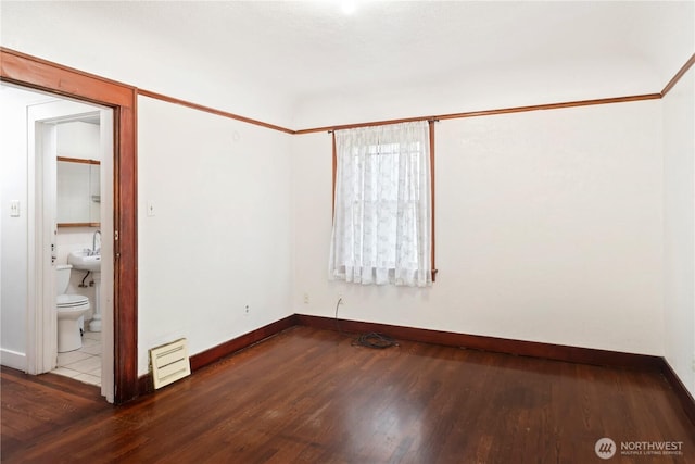 empty room featuring wood finished floors, baseboards, and a sink