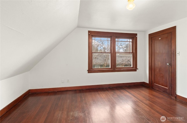 bonus room featuring dark wood finished floors, vaulted ceiling, and baseboards