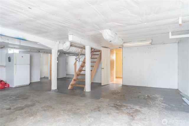 unfinished below grade area featuring stairs and freestanding refrigerator