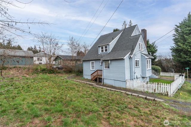 back of property featuring a lawn, a chimney, roof with shingles, and fence