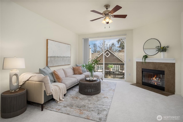 carpeted living area with a tiled fireplace and ceiling fan