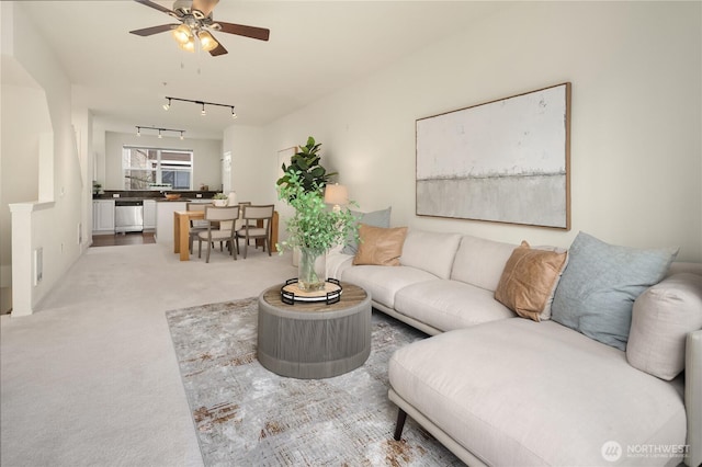 living area featuring light carpet, track lighting, and ceiling fan