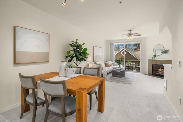 carpeted dining area featuring baseboards, a fireplace, and a ceiling fan