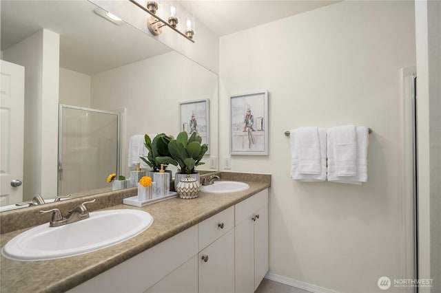 bathroom featuring double vanity, baseboards, a stall shower, and a sink