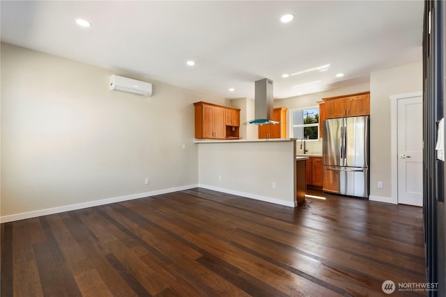 kitchen featuring recessed lighting, a peninsula, freestanding refrigerator, island range hood, and a wall mounted AC