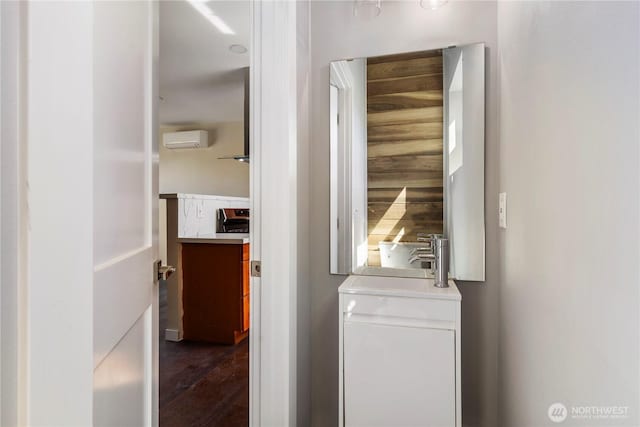 clothes washing area featuring a wall unit AC, dark wood-style flooring, and a sink