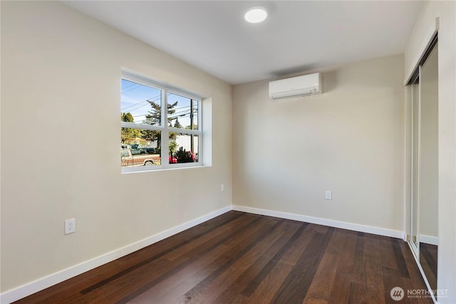 unfurnished bedroom featuring dark wood-type flooring, a closet, baseboards, and a wall mounted air conditioner