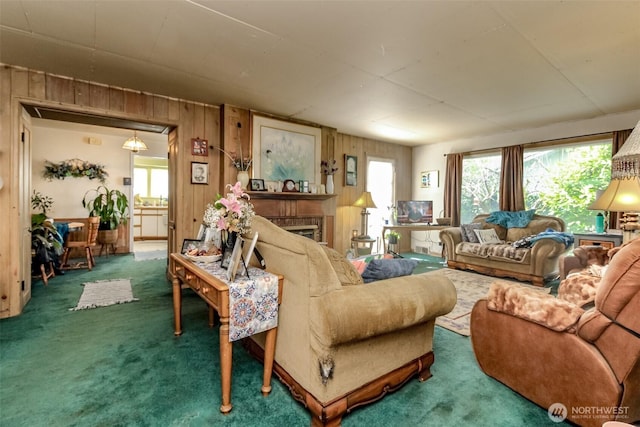 carpeted living area featuring wood walls and a fireplace