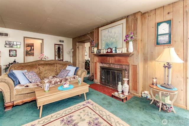 living area featuring visible vents, wood walls, a brick fireplace, and carpet