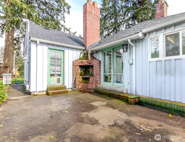 exterior space featuring a patio area, entry steps, a chimney, and board and batten siding