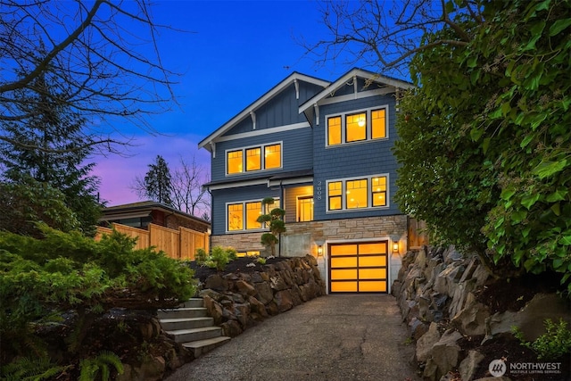 view of front of home featuring board and batten siding, concrete driveway, a garage, and stone siding