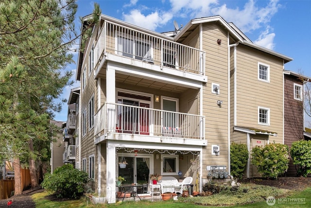 rear view of house featuring a balcony and fence