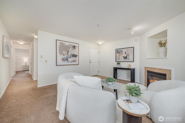 living area with baseboards, light colored carpet, and a tile fireplace