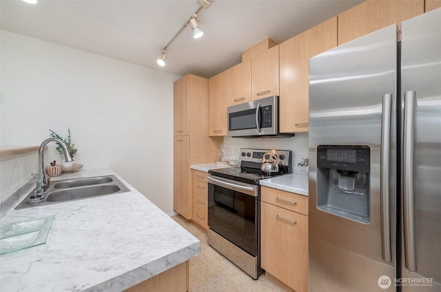 kitchen featuring track lighting, light brown cabinetry, a sink, stainless steel appliances, and light countertops