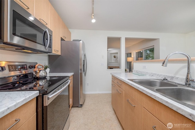 kitchen featuring track lighting, a sink, appliances with stainless steel finishes, light countertops, and baseboards