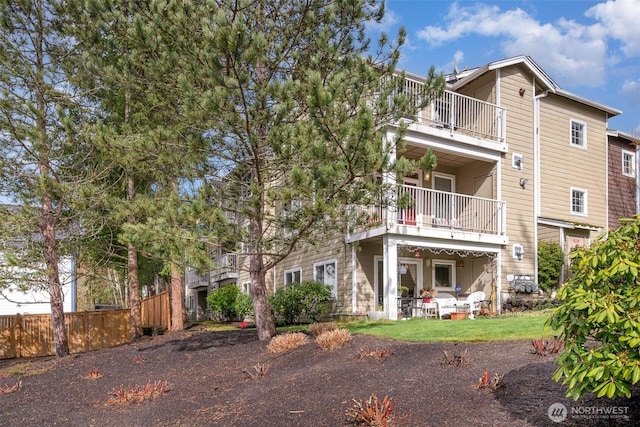 rear view of property featuring a balcony and fence