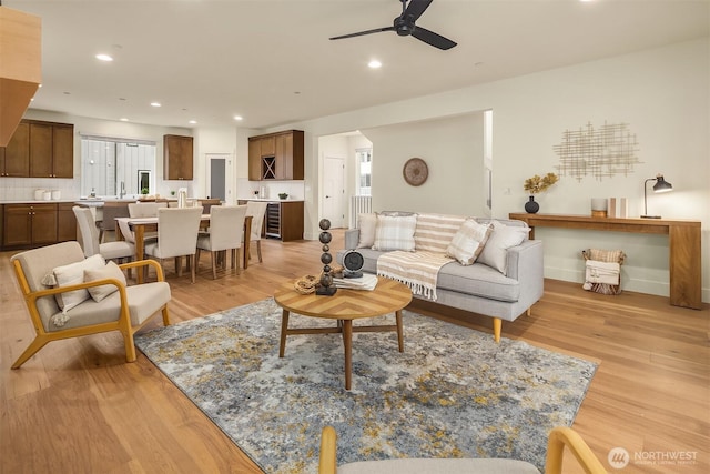 living area with recessed lighting, beverage cooler, a ceiling fan, and light wood finished floors