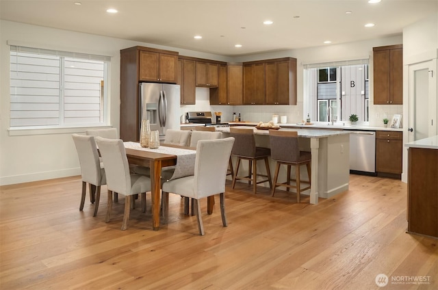 kitchen featuring tasteful backsplash, a center island, light wood-style floors, appliances with stainless steel finishes, and light countertops