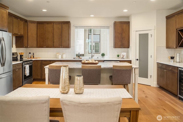 kitchen with a sink, stainless steel appliances, light wood-style floors, a breakfast bar area, and decorative backsplash