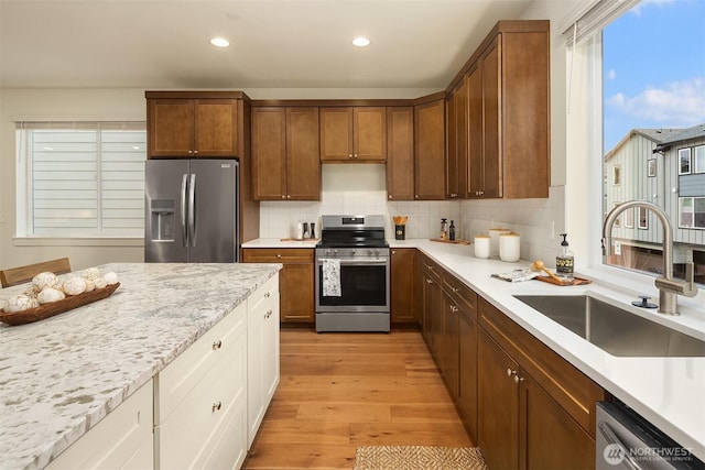 kitchen featuring recessed lighting, a sink, stainless steel appliances, light wood-style floors, and backsplash