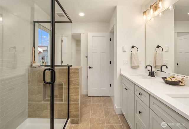 bathroom with visible vents, double vanity, recessed lighting, a stall shower, and a sink