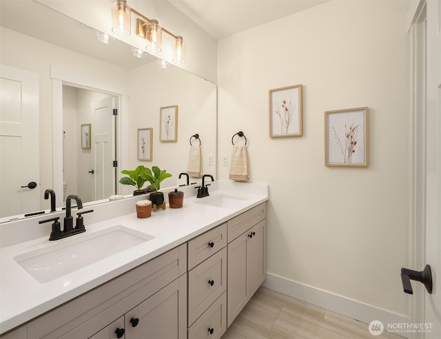 bathroom featuring a sink, baseboards, toilet, and double vanity