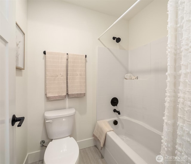 full bath with toilet, shower / bath combo with shower curtain, and baseboards