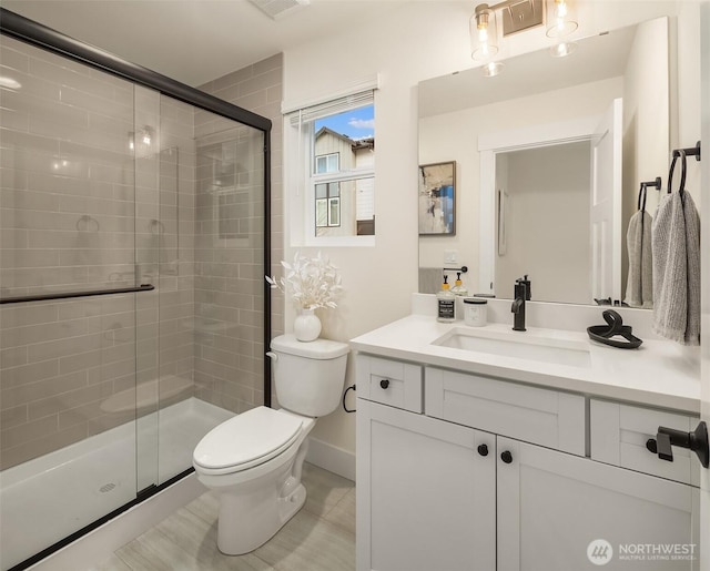 full bath with vanity, a shower stall, toilet, and baseboards