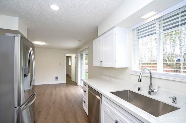 kitchen featuring a sink, plenty of natural light, appliances with stainless steel finishes, and white cabinetry