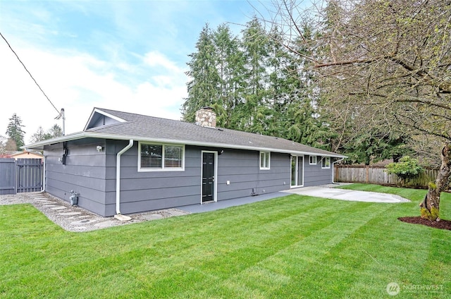 back of house with a yard, a shingled roof, fence private yard, a chimney, and a patio area