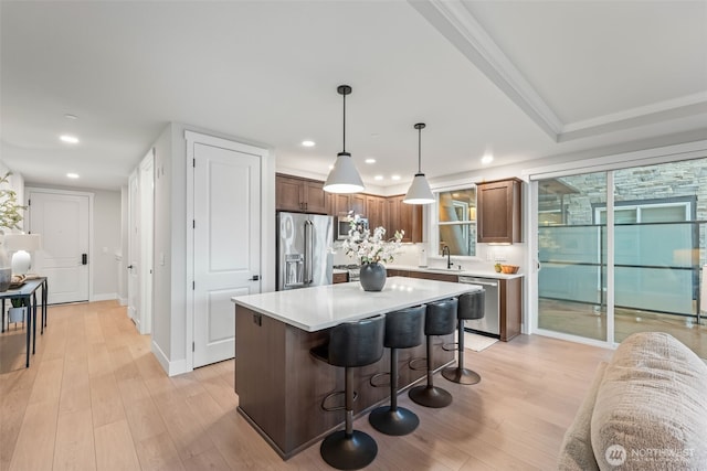 kitchen with stainless steel appliances, a kitchen bar, light wood-style flooring, and light countertops