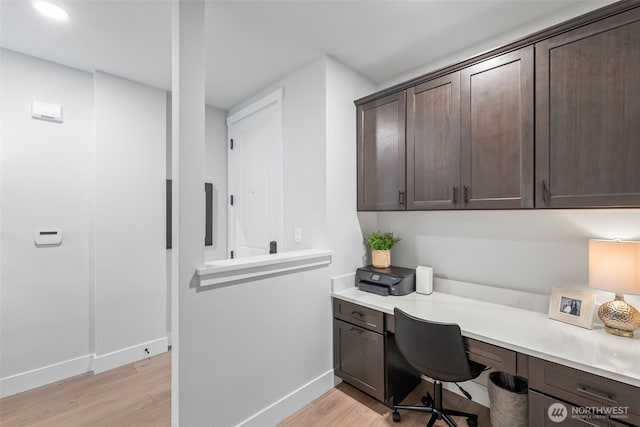 home office with light wood-style flooring, built in study area, and baseboards