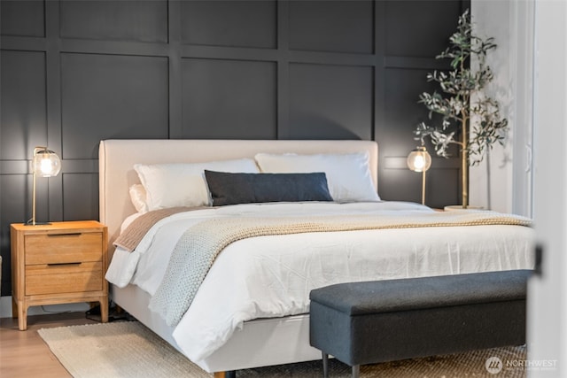 bedroom with wood finished floors and a decorative wall