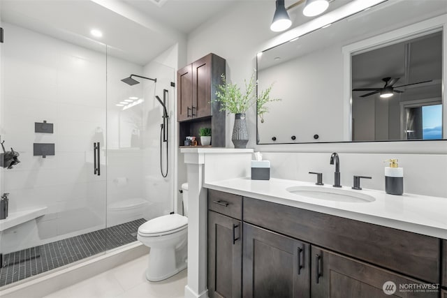 bathroom with a ceiling fan, vanity, toilet, and a shower stall