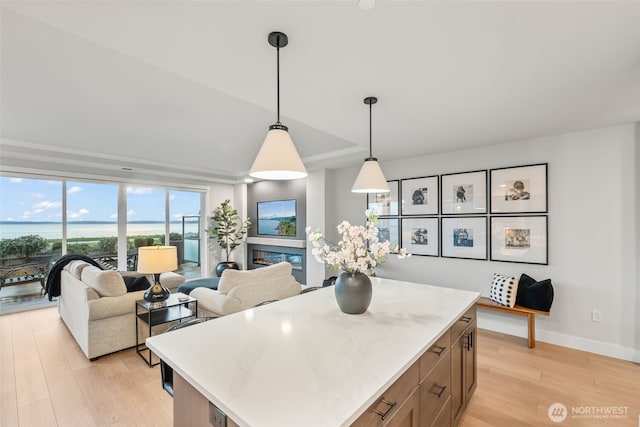 kitchen featuring light wood-type flooring, a kitchen island, open floor plan, baseboards, and hanging light fixtures