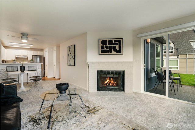 living room featuring baseboards, a ceiling fan, a fireplace, and carpet flooring