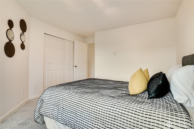 bedroom with a closet, light carpet, and baseboards