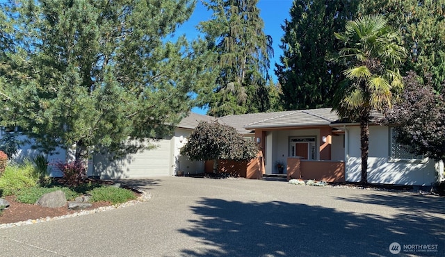 view of front facade with aphalt driveway, stucco siding, an attached garage, and a tile roof