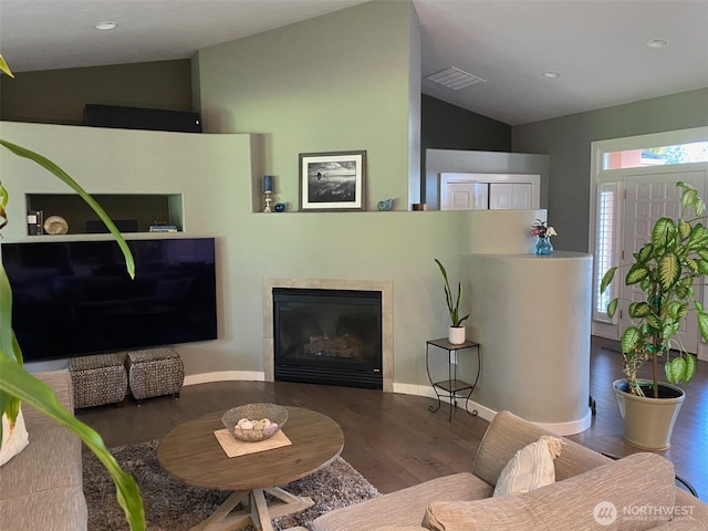 living room featuring a glass covered fireplace, visible vents, wood finished floors, and vaulted ceiling