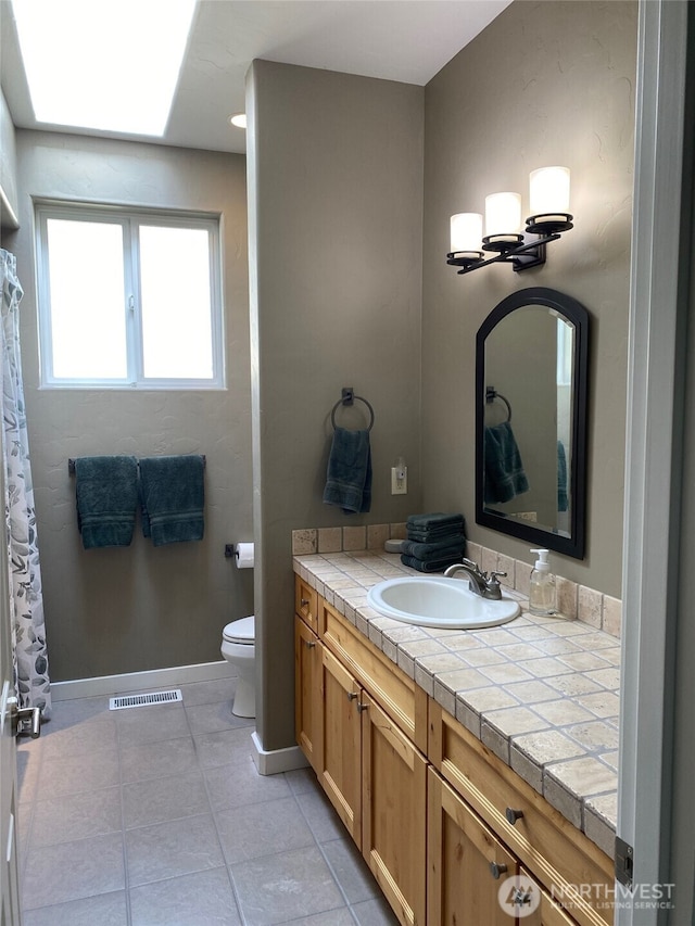 bathroom with vanity, visible vents, baseboards, tile patterned floors, and toilet