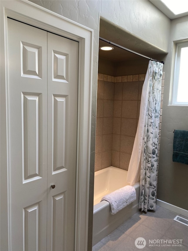 bathroom featuring visible vents, shower / bath combination with curtain, and baseboards