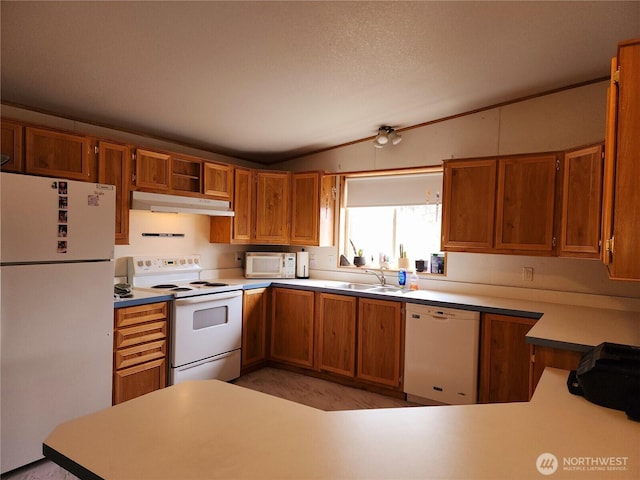 kitchen with under cabinet range hood, white appliances, lofted ceiling, and brown cabinetry