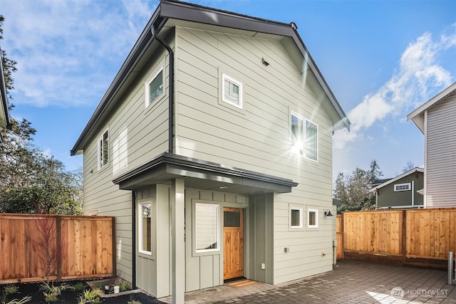 rear view of house featuring a patio area, board and batten siding, and a fenced backyard